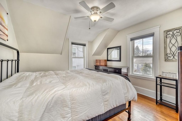 bedroom featuring multiple windows, wood finished floors, lofted ceiling, baseboards, and ceiling fan