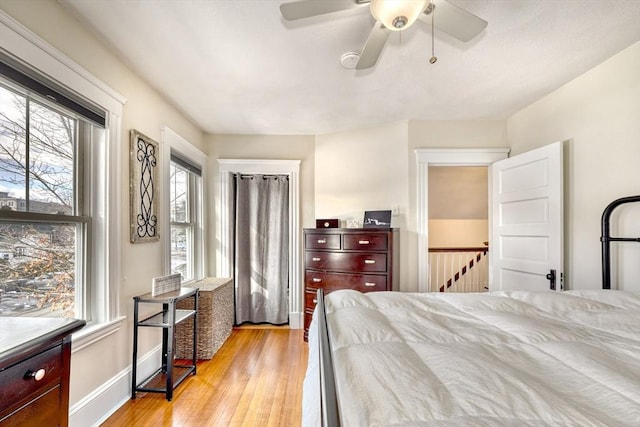 bedroom featuring multiple windows, light wood-style floors, ceiling fan, and baseboards