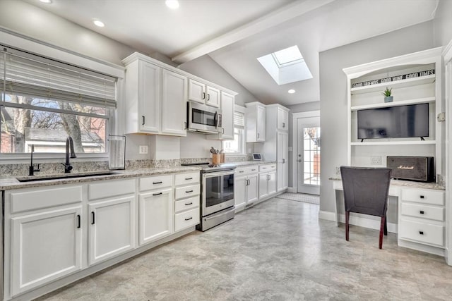 kitchen with stainless steel appliances, a skylight, a sink, white cabinets, and light stone counters