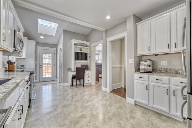 kitchen with a skylight, stainless steel appliances, baseboards, white cabinets, and light stone counters