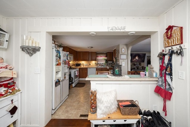 kitchen with white appliances, kitchen peninsula, and light tile patterned floors