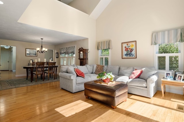 living room featuring light hardwood / wood-style flooring, a high ceiling, and an inviting chandelier