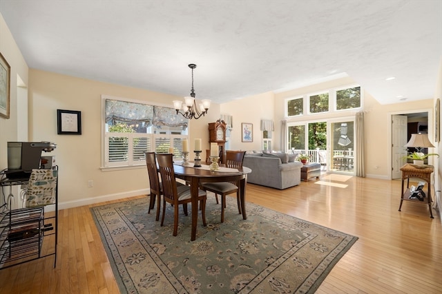 dining room with a healthy amount of sunlight, light hardwood / wood-style floors, and a chandelier