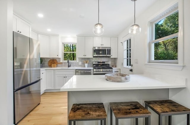 kitchen with a kitchen bar, white cabinetry, sink, and appliances with stainless steel finishes