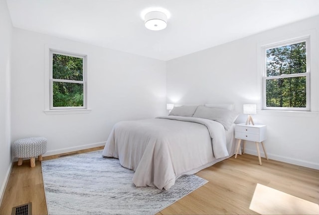 bedroom with light wood-type flooring and multiple windows