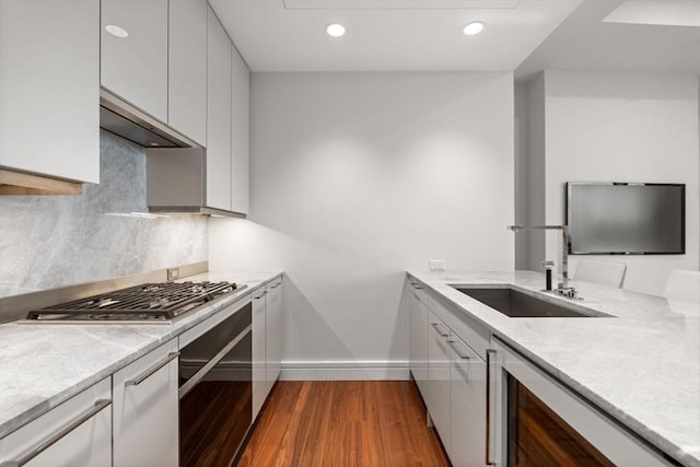 kitchen with dark wood-type flooring, wall oven, decorative backsplash, stainless steel gas stovetop, and sink