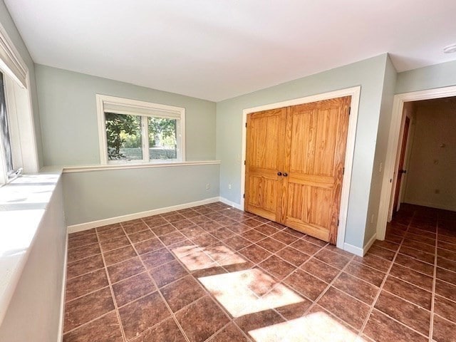 unfurnished bedroom with dark tile patterned flooring and a closet