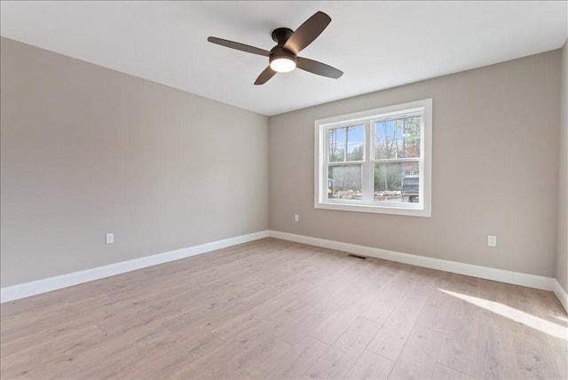 empty room featuring light wood-type flooring, ceiling fan, visible vents, and baseboards