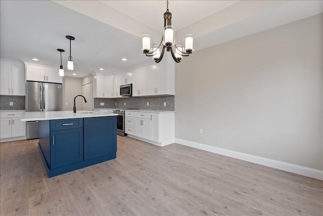 kitchen featuring a sink, white cabinets, light countertops, appliances with stainless steel finishes, and hanging light fixtures