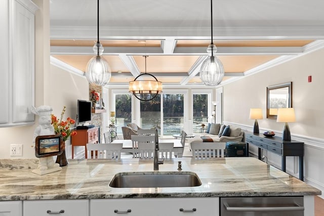 kitchen with a sink, coffered ceiling, ornamental molding, white cabinets, and open floor plan