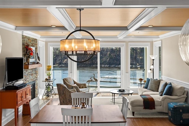 living area with crown molding, beamed ceiling, a chandelier, coffered ceiling, and wood finished floors