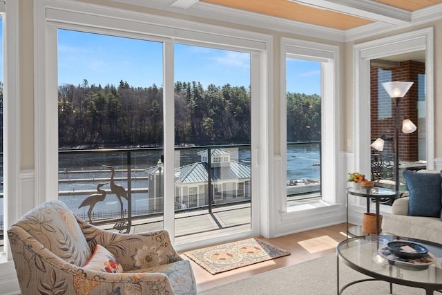 sunroom / solarium featuring wood finished floors, a decorative wall, ornamental molding, and wainscoting