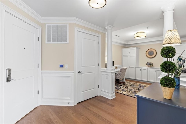 entrance foyer with visible vents, a decorative wall, decorative columns, wood finished floors, and wainscoting