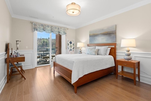 bedroom with light wood-style flooring, ornamental molding, access to outside, and wainscoting