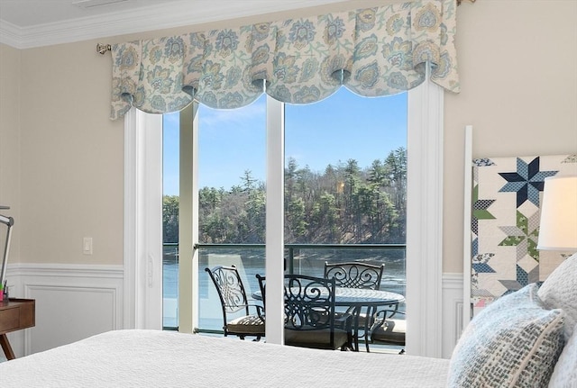 bedroom with a wainscoted wall, crown molding, and a decorative wall