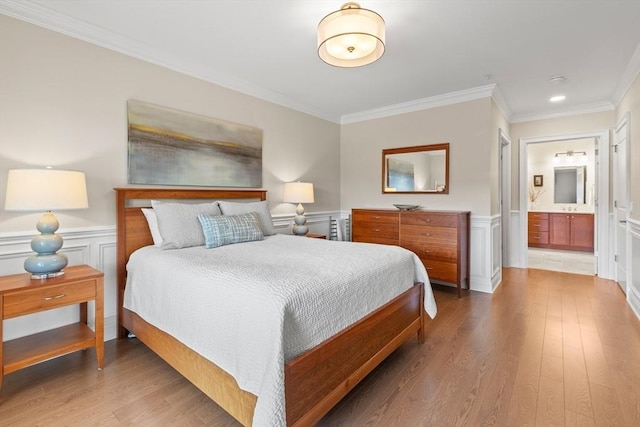 bedroom featuring wood finished floors, a wainscoted wall, and ornamental molding