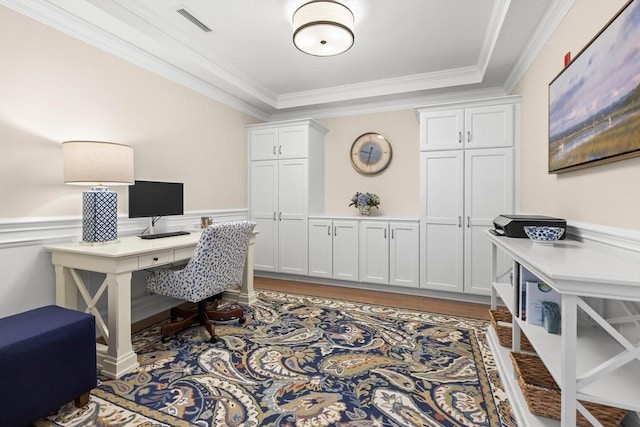 office space featuring wood finished floors, visible vents, crown molding, and a wainscoted wall