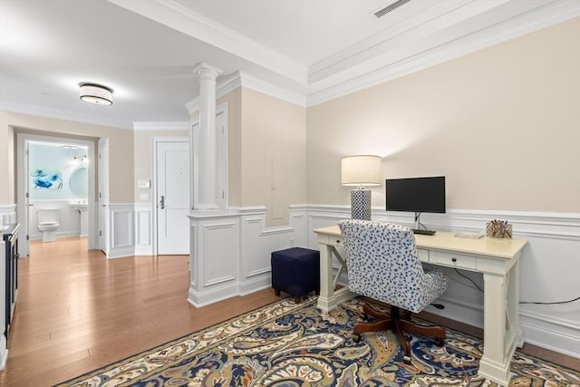 office featuring visible vents, ornate columns, ornamental molding, wainscoting, and wood finished floors