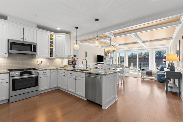 kitchen featuring white cabinetry, a sink, stainless steel appliances, open floor plan, and a peninsula