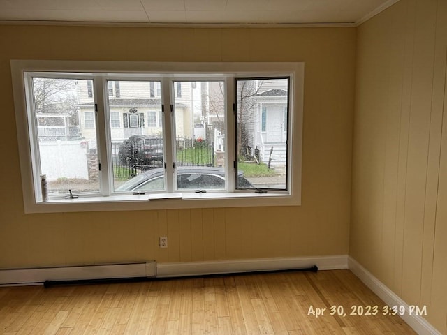 empty room with baseboard heating and light hardwood / wood-style flooring