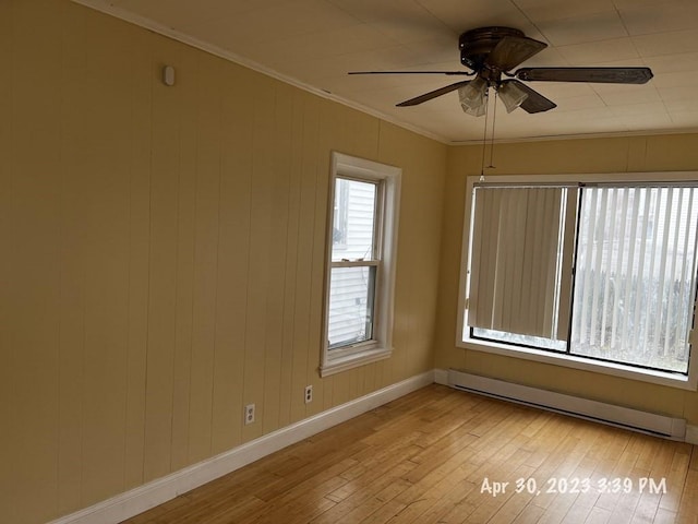 spare room featuring ornamental molding, light hardwood / wood-style floors, ceiling fan, and a baseboard heating unit