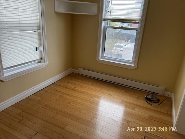 empty room featuring light wood-type flooring and baseboard heating