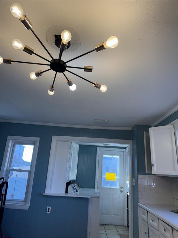 kitchen featuring an inviting chandelier, light tile patterned flooring, white cabinetry, and tasteful backsplash