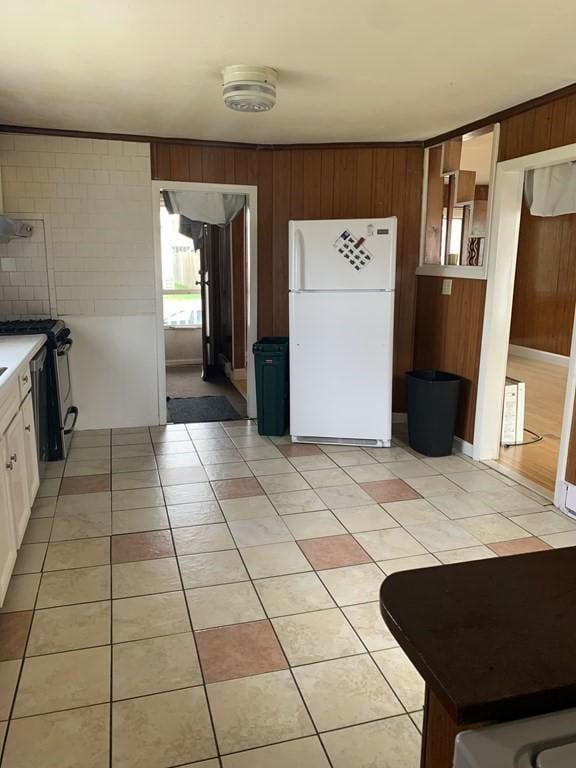 kitchen with wood walls, stainless steel range, white cabinets, and white refrigerator