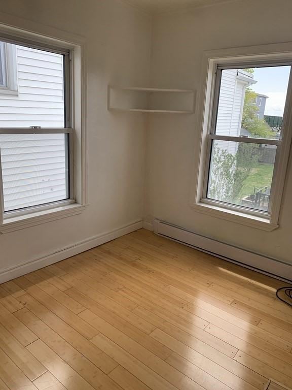 unfurnished room with light wood-type flooring and baseboard heating