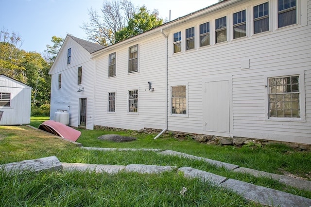 back of property featuring a yard and a shed