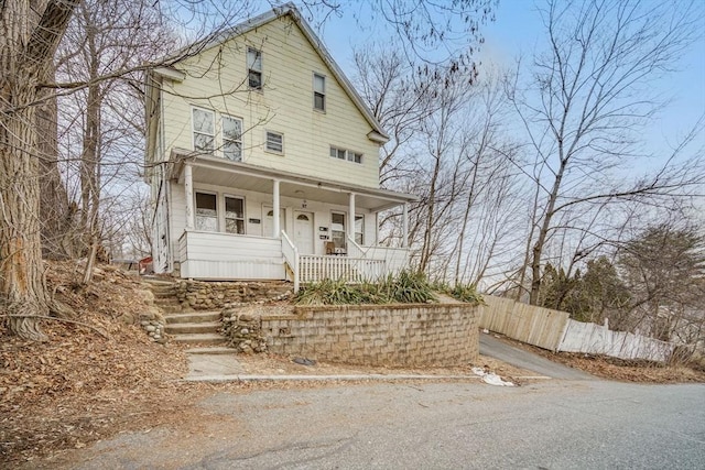 view of front of house featuring covered porch and fence