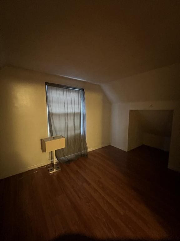 bonus room with vaulted ceiling and dark wood-type flooring