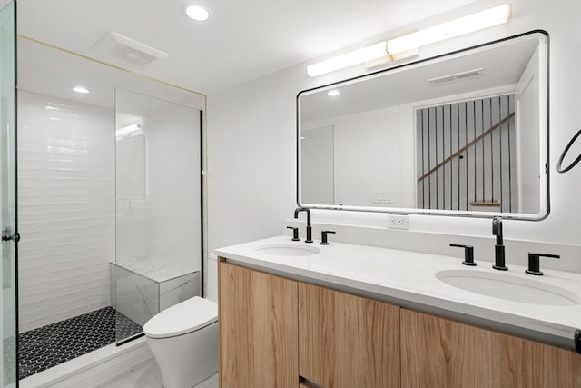 bathroom with vanity, toilet, and a tile shower