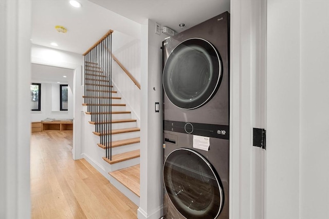 laundry room featuring stacked washer and clothes dryer and light wood-type flooring