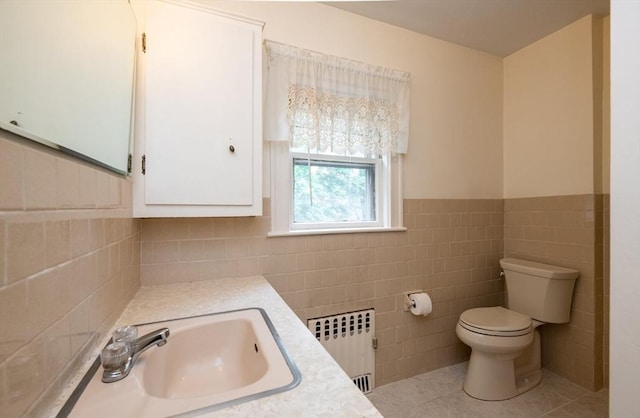 47 Ronald Rd, Arlington, MA 02474 - bathroom featuring radiator heating unit, toilet, tile patterned flooring, tile walls, and vanity
