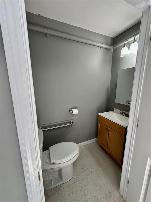 half bathroom featuring vanity, toilet, and baseboards