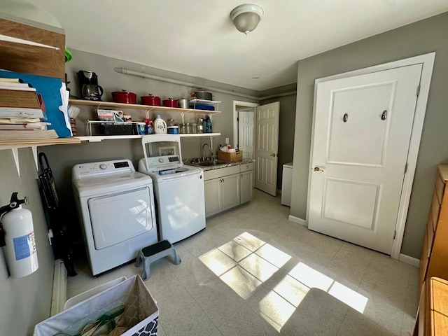 clothes washing area with cabinet space, a sink, washer and clothes dryer, and baseboards