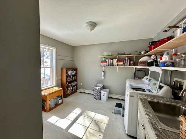 laundry room with cabinet space, a baseboard heating unit, washing machine and dryer, a sink, and baseboards