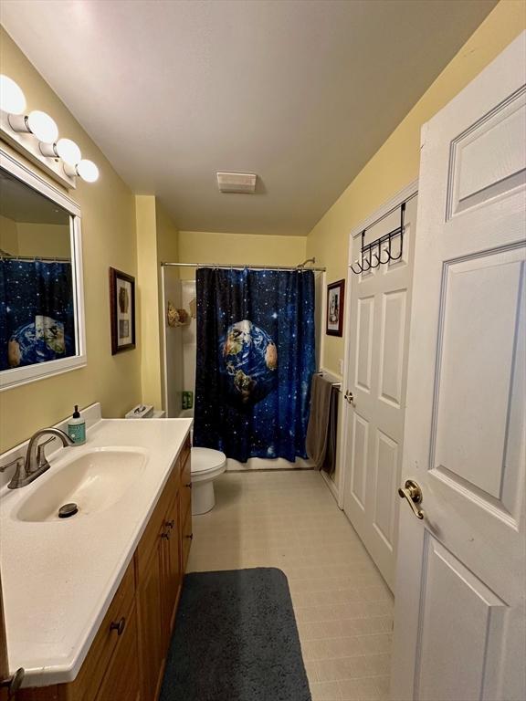 bathroom with toilet, a shower with curtain, tile patterned floors, and vanity