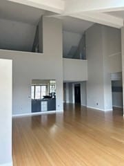 unfurnished living room with hardwood / wood-style floors, beam ceiling, and high vaulted ceiling