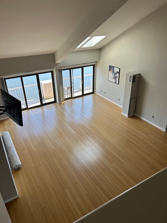 unfurnished living room with light hardwood / wood-style floors and lofted ceiling with skylight