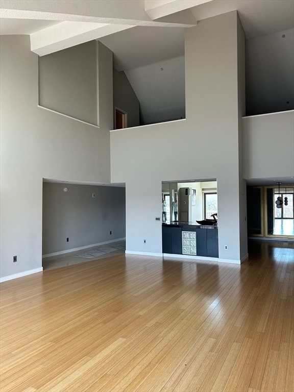 unfurnished living room featuring light hardwood / wood-style flooring and high vaulted ceiling