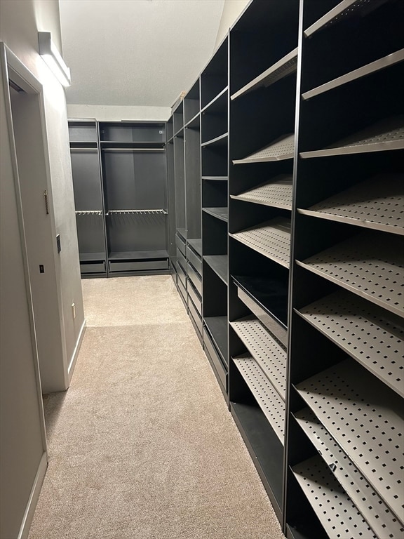 walk in closet featuring light colored carpet