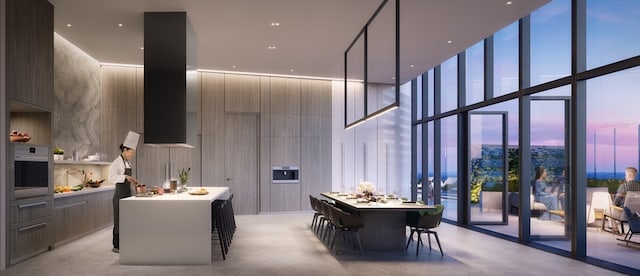 kitchen with a towering ceiling, stainless steel oven, a kitchen bar, and a kitchen island