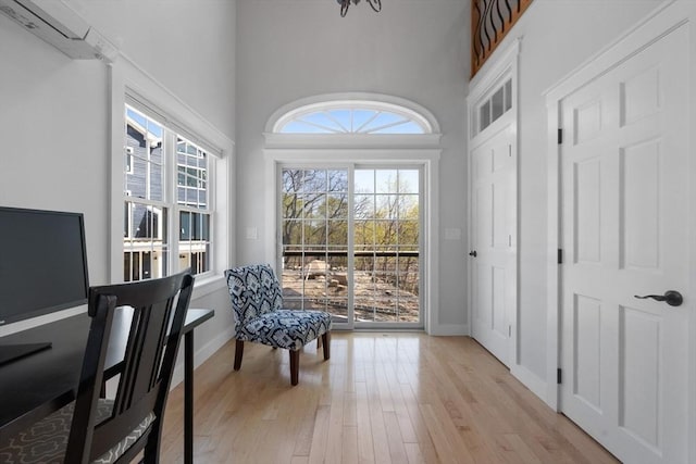 interior space with baseboards, light wood finished floors, and a high ceiling