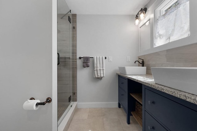 full bath featuring tile patterned flooring, double vanity, baseboards, a sink, and a stall shower
