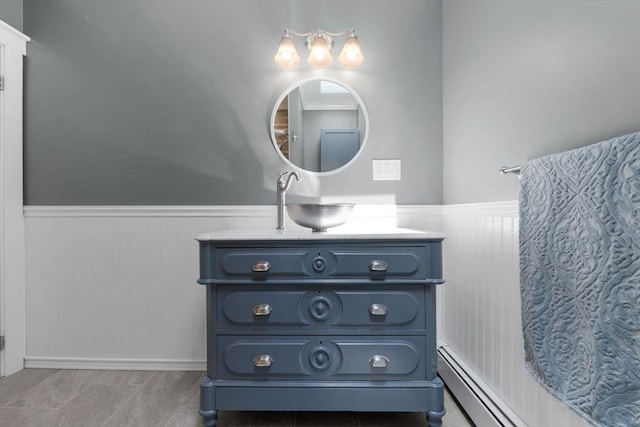 bathroom featuring vanity, baseboard heating, tile patterned flooring, and a wainscoted wall