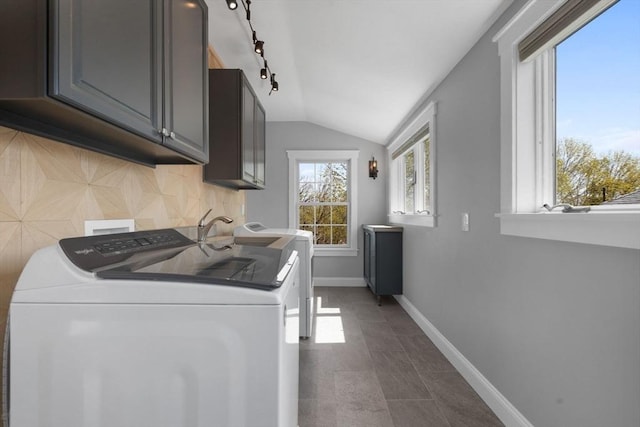 clothes washing area with baseboards, rail lighting, cabinet space, and washer and dryer