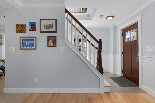 entryway featuring stairs, ornamental molding, wainscoting, and wood finished floors