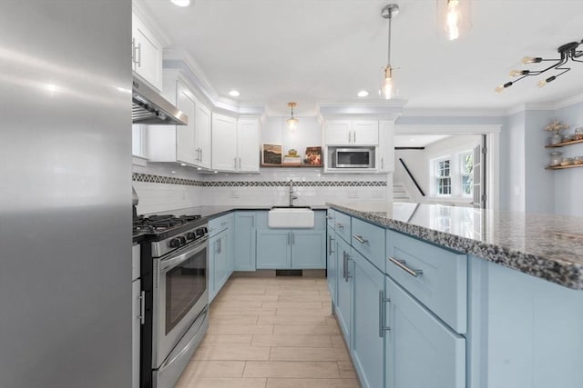 kitchen with wall chimney exhaust hood, stainless steel appliances, white cabinetry, decorative backsplash, and blue cabinets